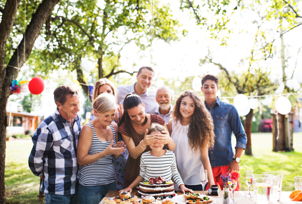 Family celebration outside in the backyard.Big garden party. Birthday party. Small girl with a birthday cake.