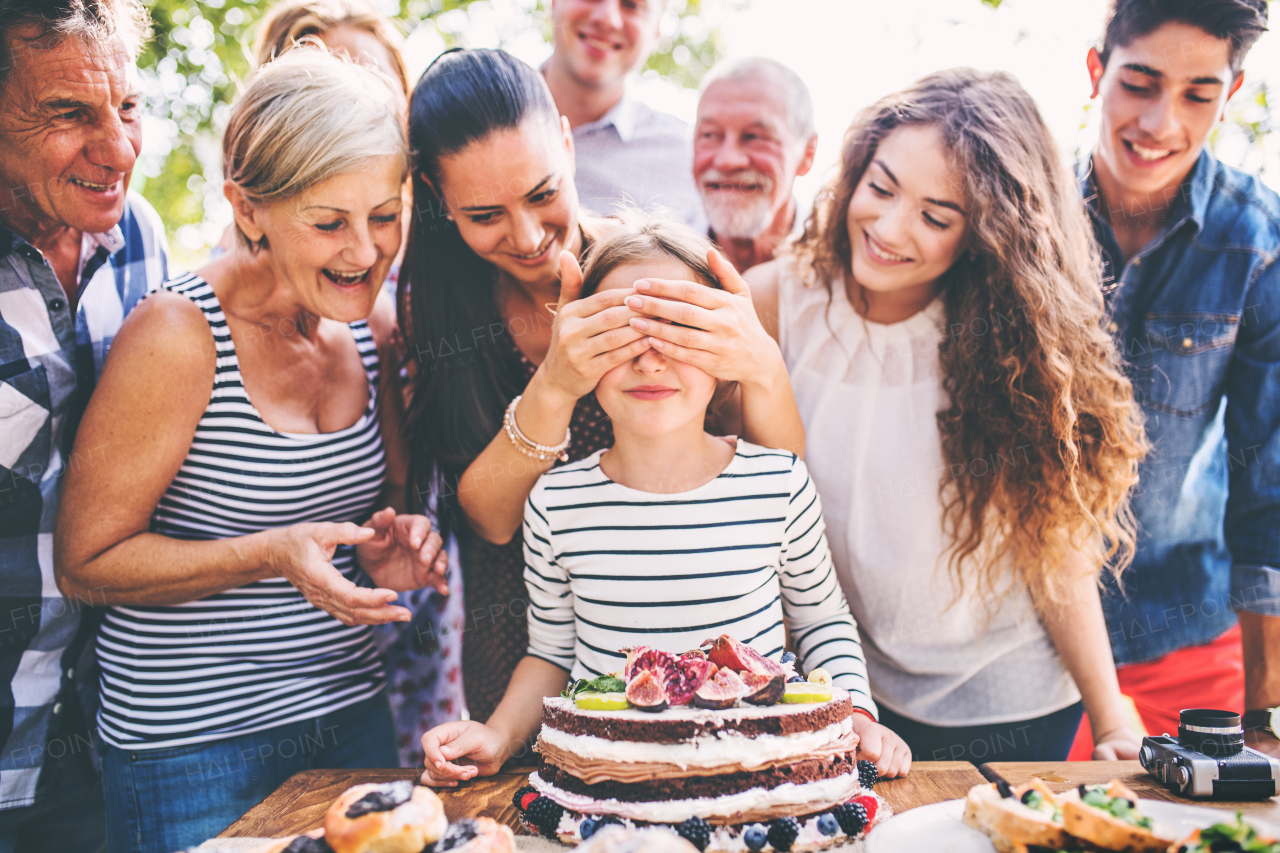 Family celebration outside in the backyard.Big garden party. Birthday party. Small girl with a birthday cake.