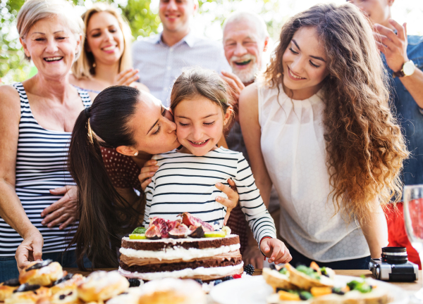 Family celebration outside in the backyard.Big garden party. Birthday party. Small girl with a birthday cake.