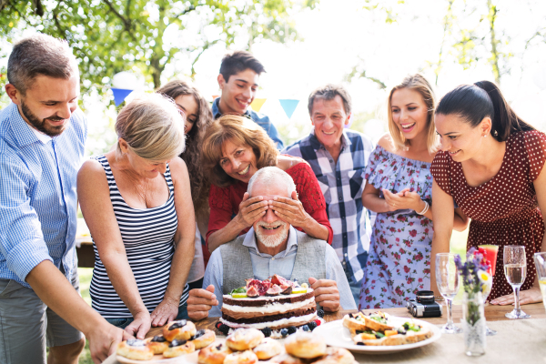 Family celebration outside in the backyard. Big garden party. Birthday party of a senior man.