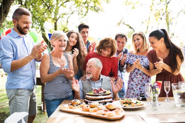 Family celebration outside in the backyard. Big garden party. Birthday party of a senior man.