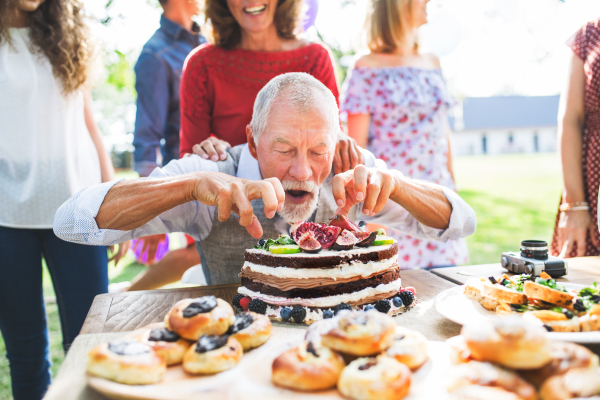 Family celebration outside in the backyard. Big garden party. Birthday party of a senior man.