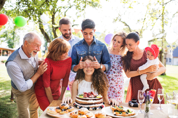 Family celebration outside in the backyard. Big garden party. Birthday party. A teenage girl with a birthday cake.