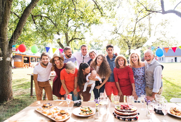 Family celebration outside in the backyard. Big garden party. Birthday party. Family posing for the photo.