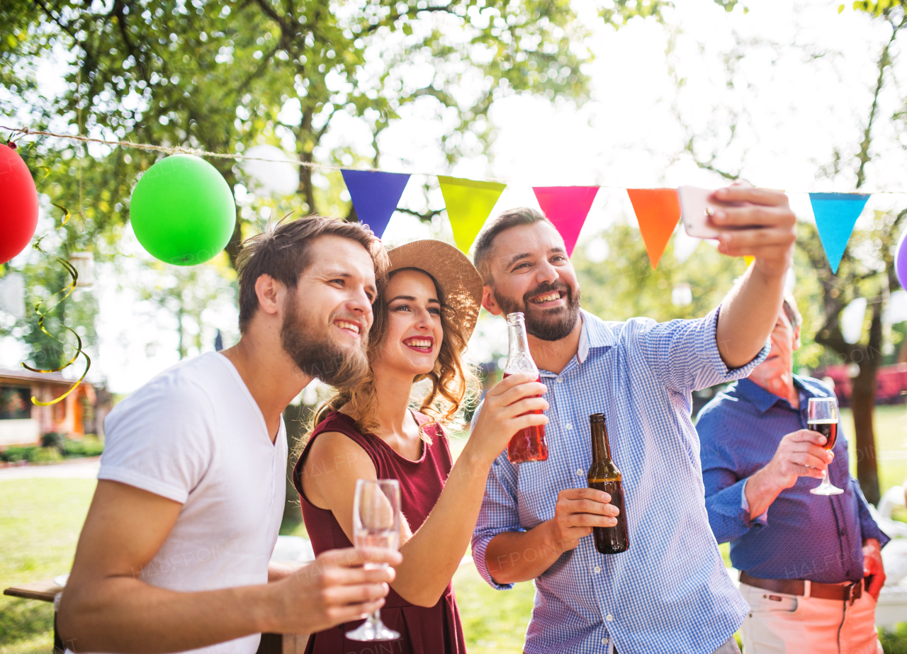 Happy young people taking selfie at a party outside in the backyard.