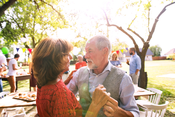 A senior couple dancing on a garden party or family celebration outside in the backyard.