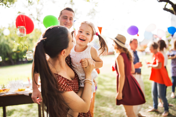 Family celebration outside in the backyard. Big garden party or birthday party. Young mother holding a small girl.