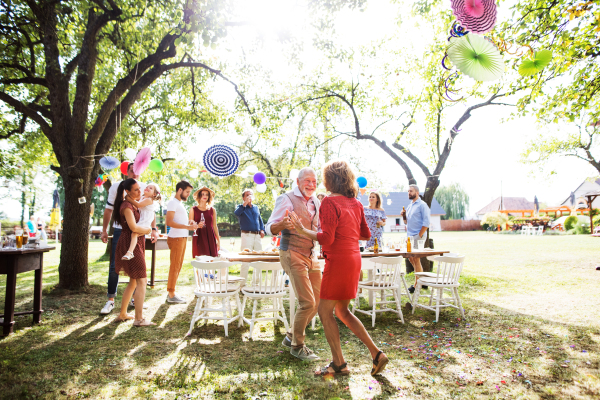 A senior couple dancing on a garden party or family celebration outside in the backyard.