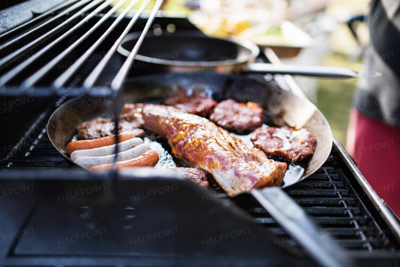 Meat and sausages on the grill. Family celebration outside in the backyard. Big garden party.