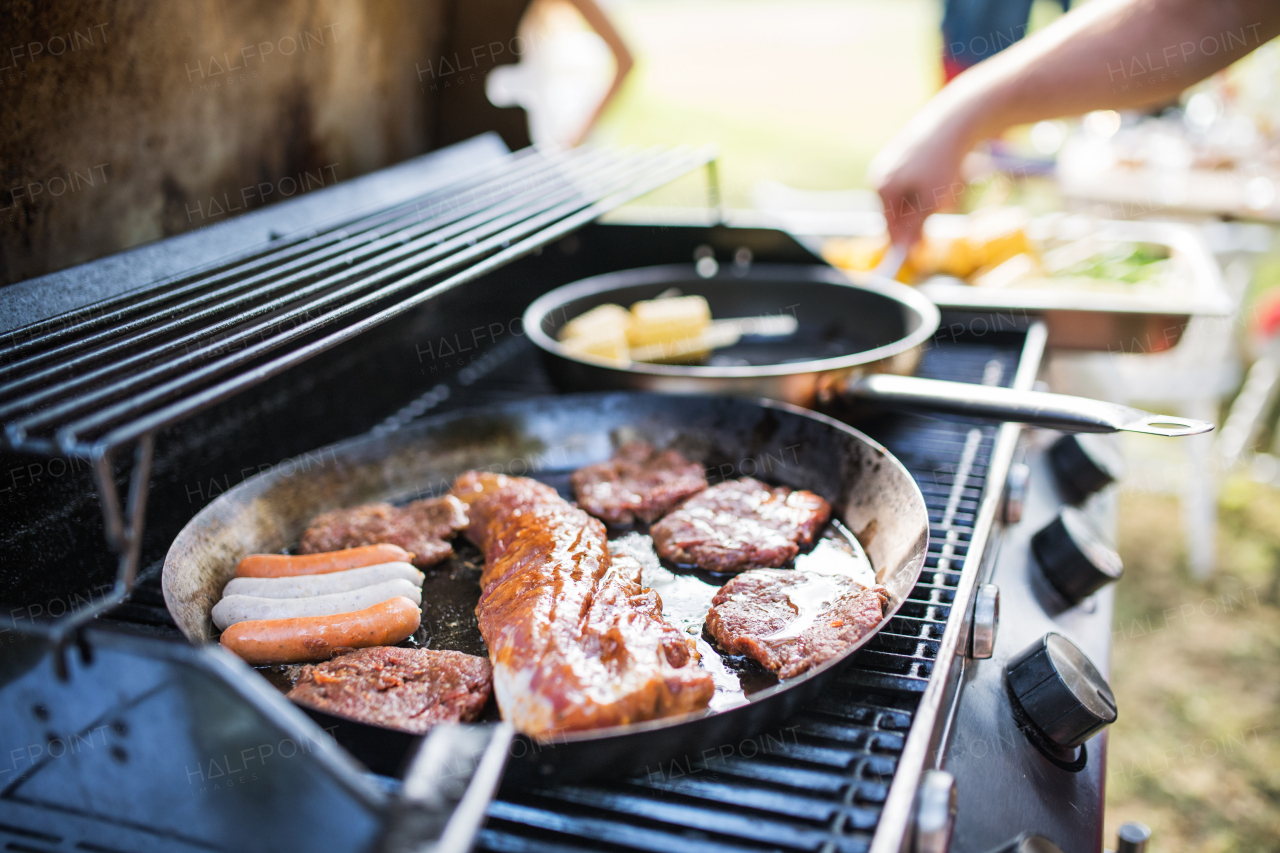 Meat and sausages on the grill. Family celebration outside in the backyard. Big garden party.