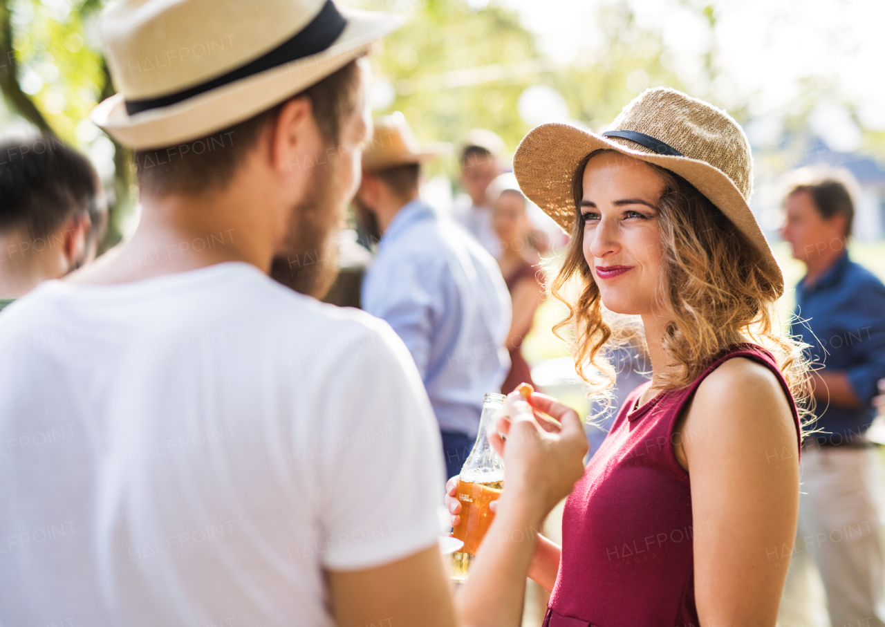 Young couple with hats eating and talking on a family celebration outside in the backyard. Barbecue party.