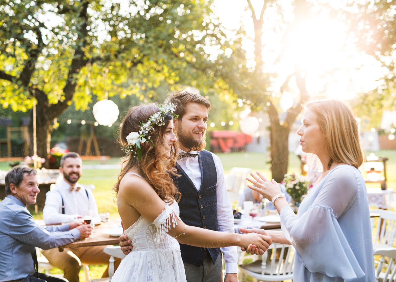 Young girl congratulating bride and groom at wedding reception outside in the backyard.