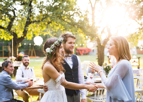 Young girl congratulating bride and groom at wedding reception outside in the backyard.