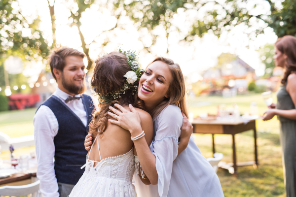 Young girl congratulating bride and groom at wedding reception outside in the backyard.