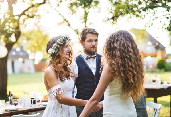 Young girl congratulating bride and groom at wedding reception outside in the backyard.