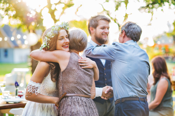 Guests congratulating happy bride and groom at wedding reception outside in the backyard.