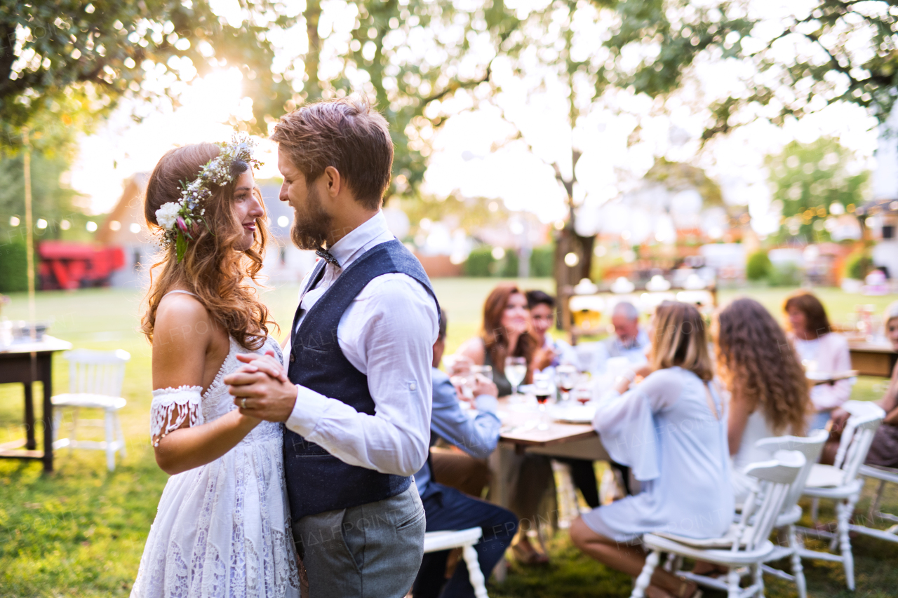 Wedding reception outside in the backyard. Bride and groom with a family dancing.