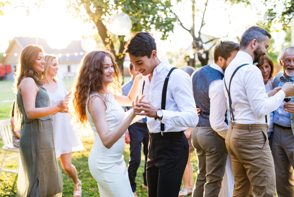 Wedding reception outside in the backyard. Guests with a family dancing.