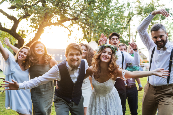 Wedding reception outside in the backyard. Family celebration. Bride, groom and their guests posing for the photo.