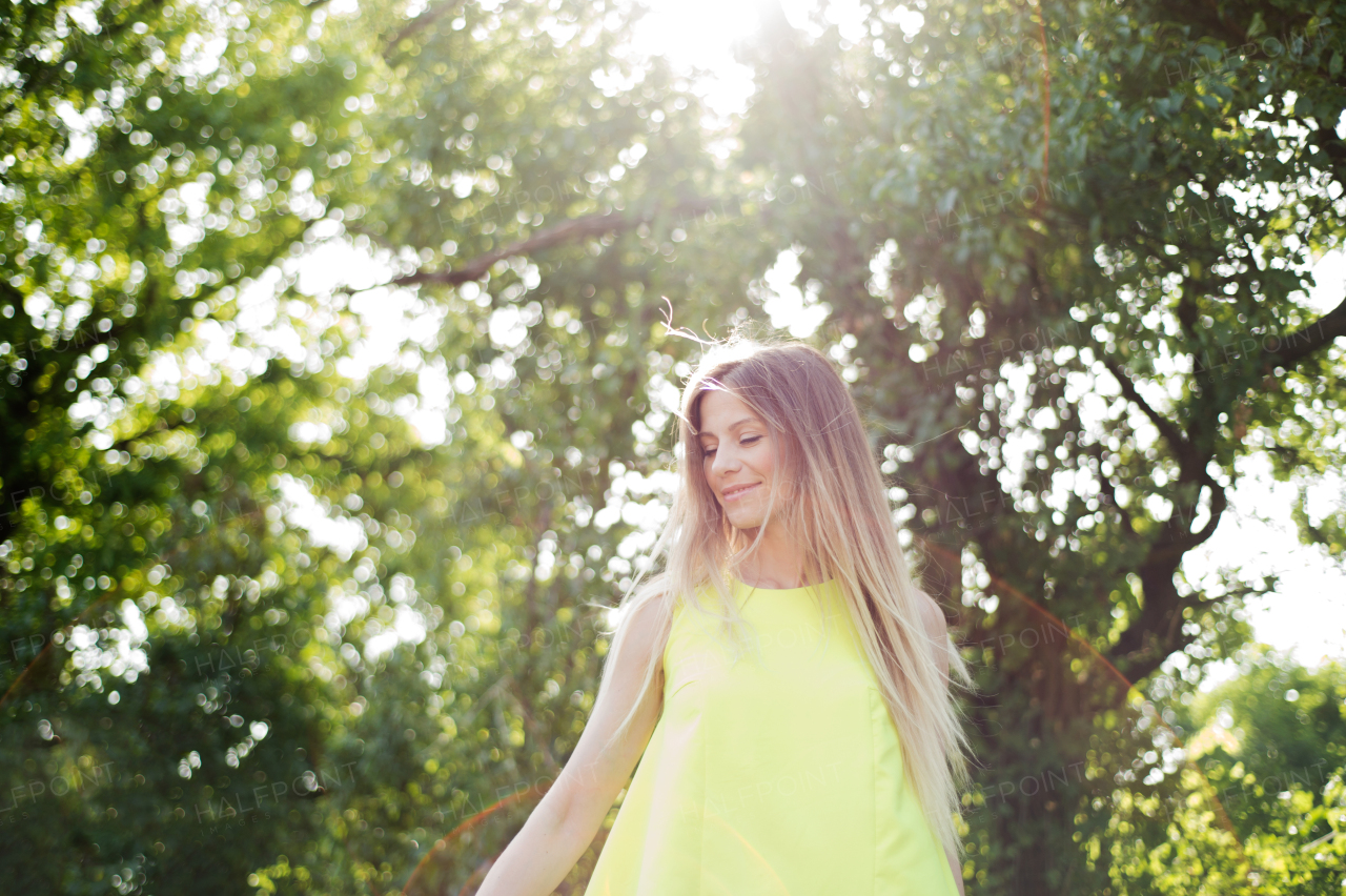 Beautiful young woman with long blowing blonde hair in neon yellow tank top. Sunny summer day.