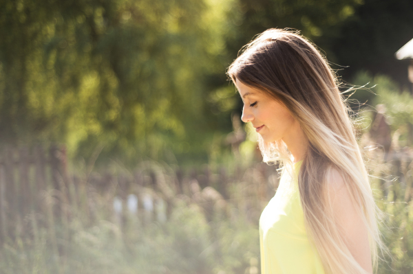 Beautiful young woman with long blonde hair in neon yellow tank top. Sunny summer day.