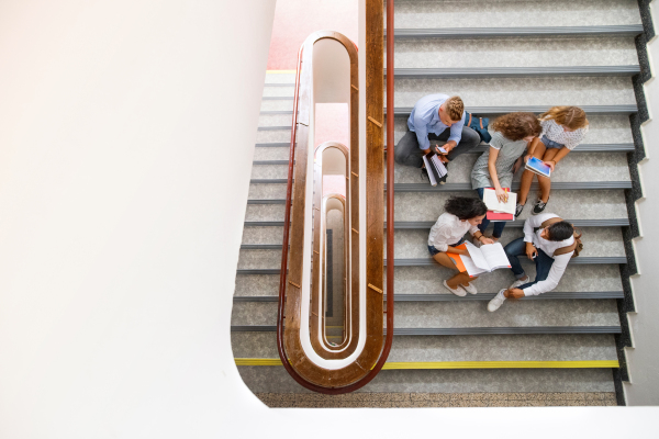 Group of attractive teenage students on stairs in high school.