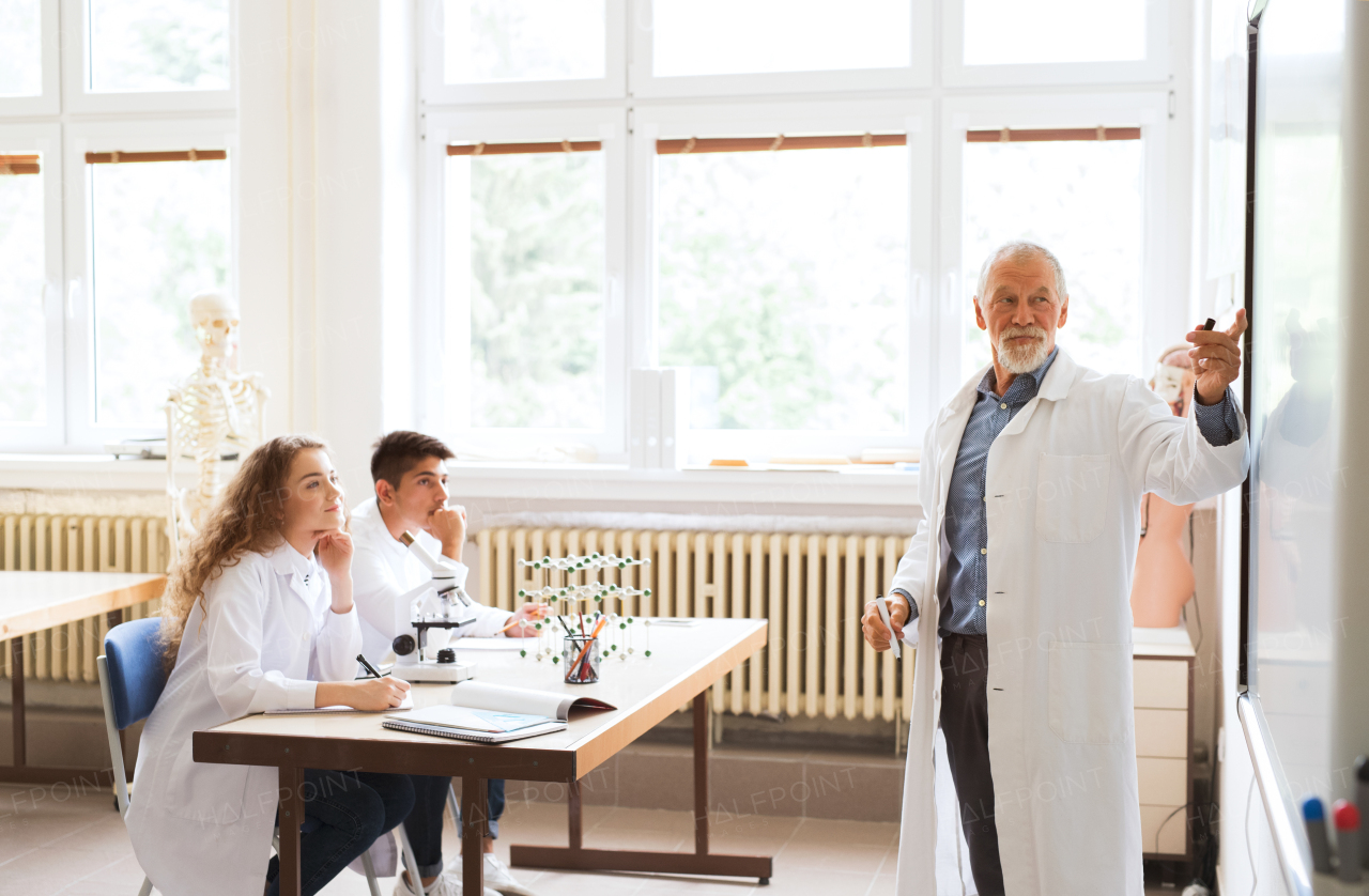 Senior teacher teaching biology to his high school students in laboratory.