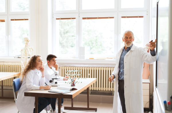 Senior teacher teaching biology to his high school students in laboratory.