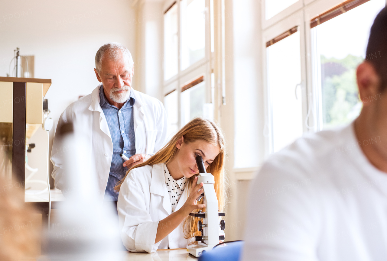 Senior teacher teaching biology to his high school student in laboratory.