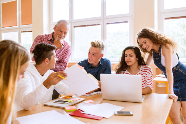 Group of high school student and their teacher with laptop studying.