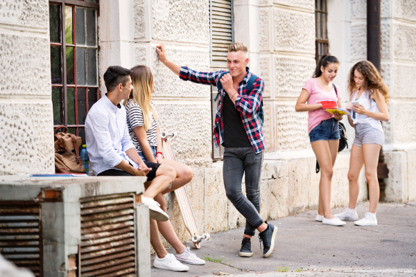 Group attractive teenage students talking in front of university.