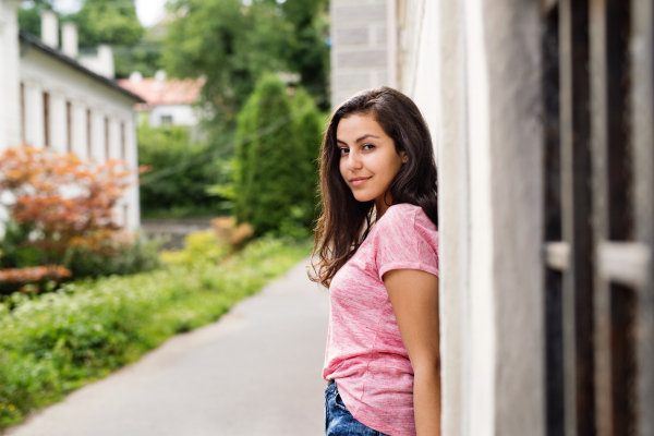 Beautiful teenage student outdoors standing at the concrete wall.