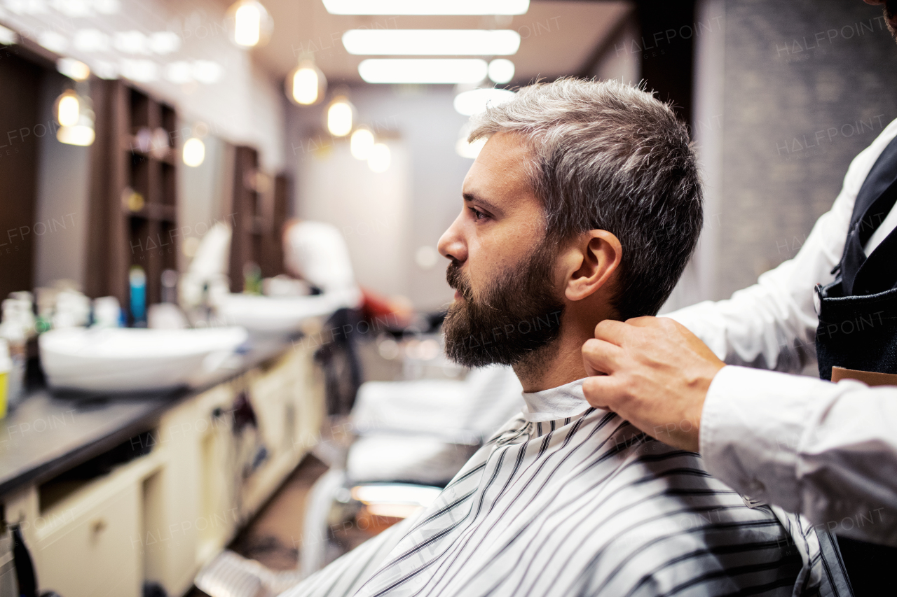 Handsome hipster man client visiting haidresser and hairstylist in barber shop.