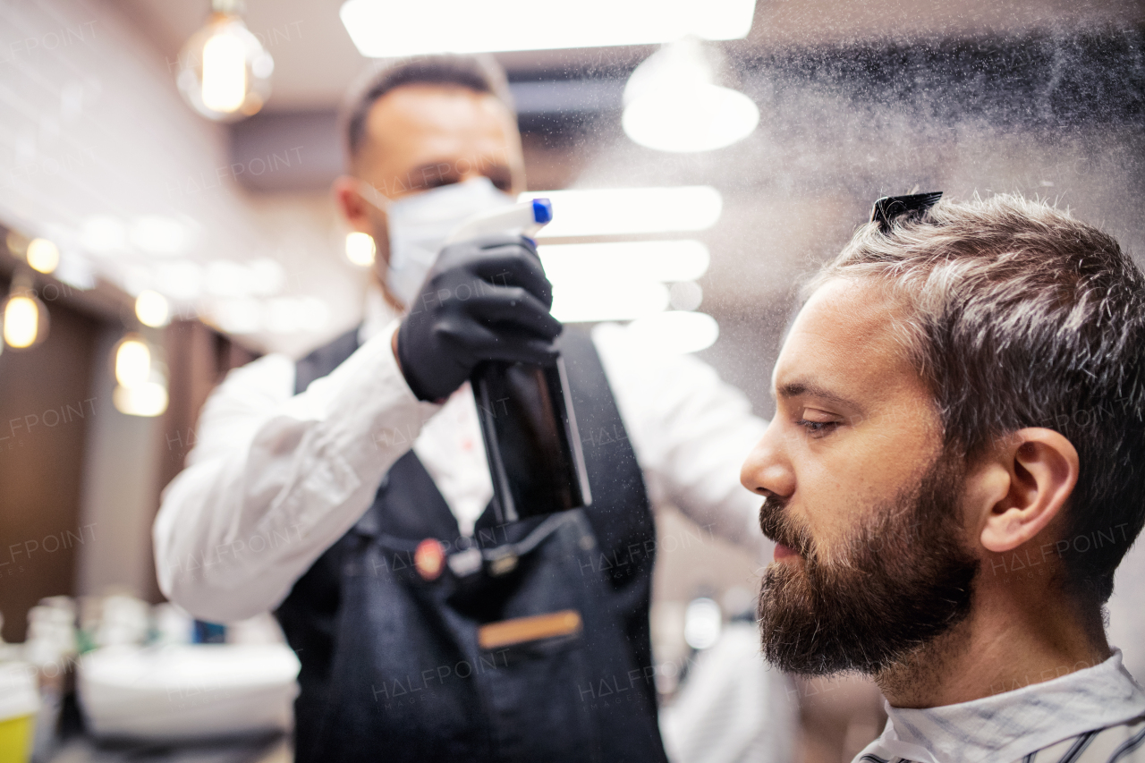 Handsome hipster man client visiting haidresser and hairstylist in barber shop.