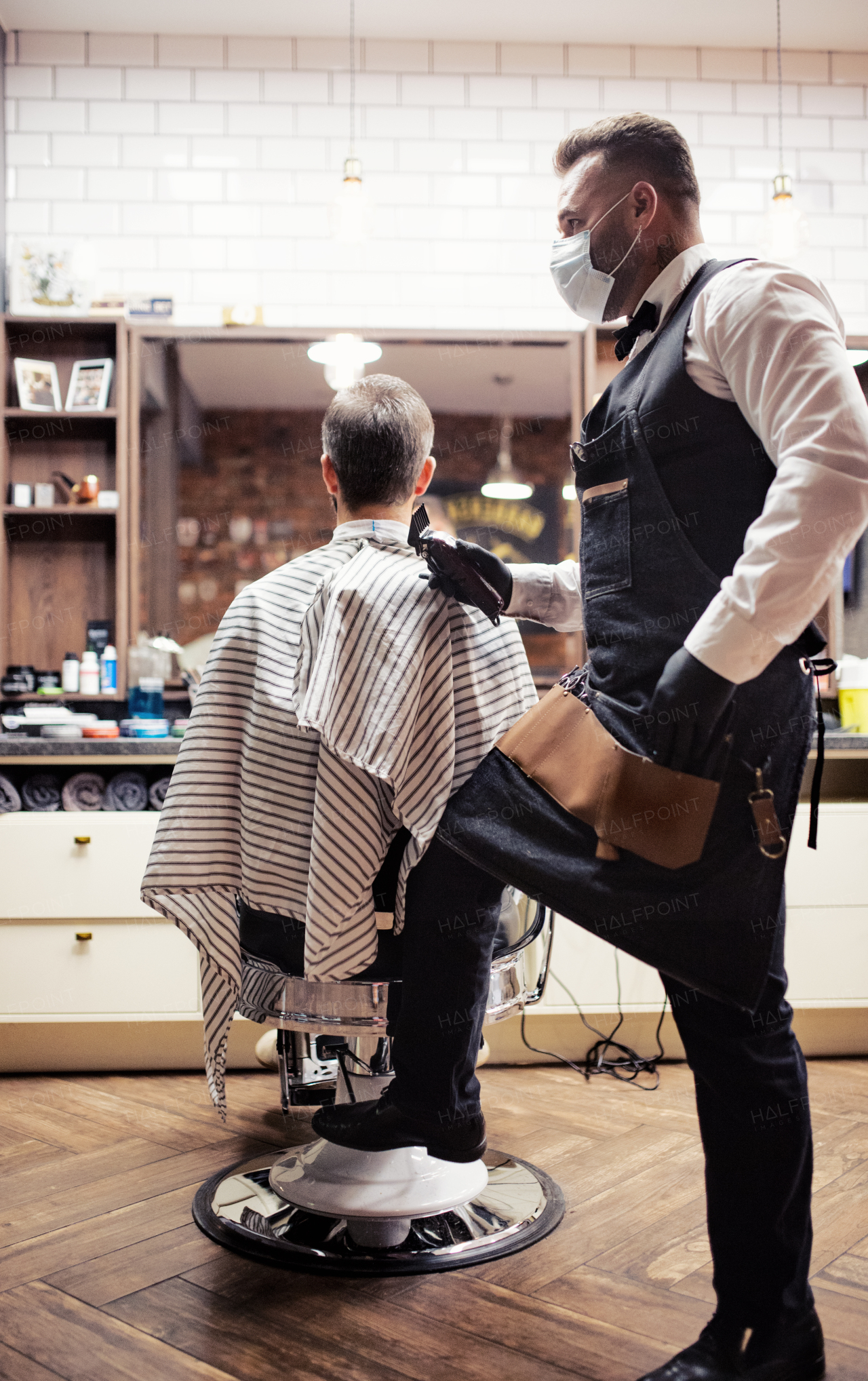 Handsome hipster man client visiting haidresser and hairstylist in barber shop.