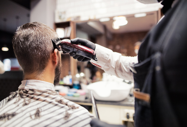 Handsome hipster man client visiting haidresser and hairstylist in barber shop.