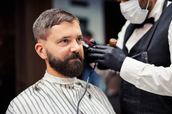 Handsome hipster man client visiting haidresser and hairstylist in barber shop.