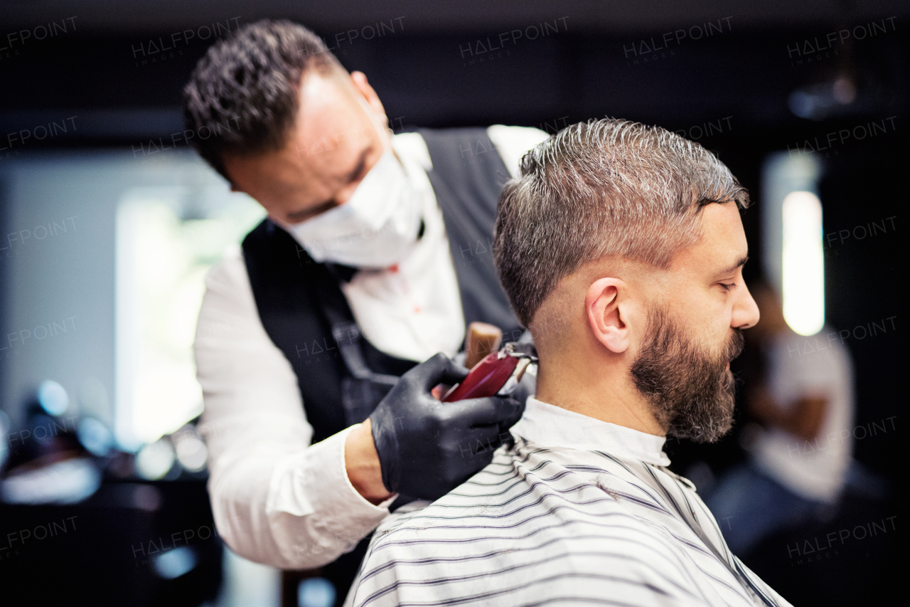 Handsome hipster man client visiting haidresser and hairstylist in barber shop.