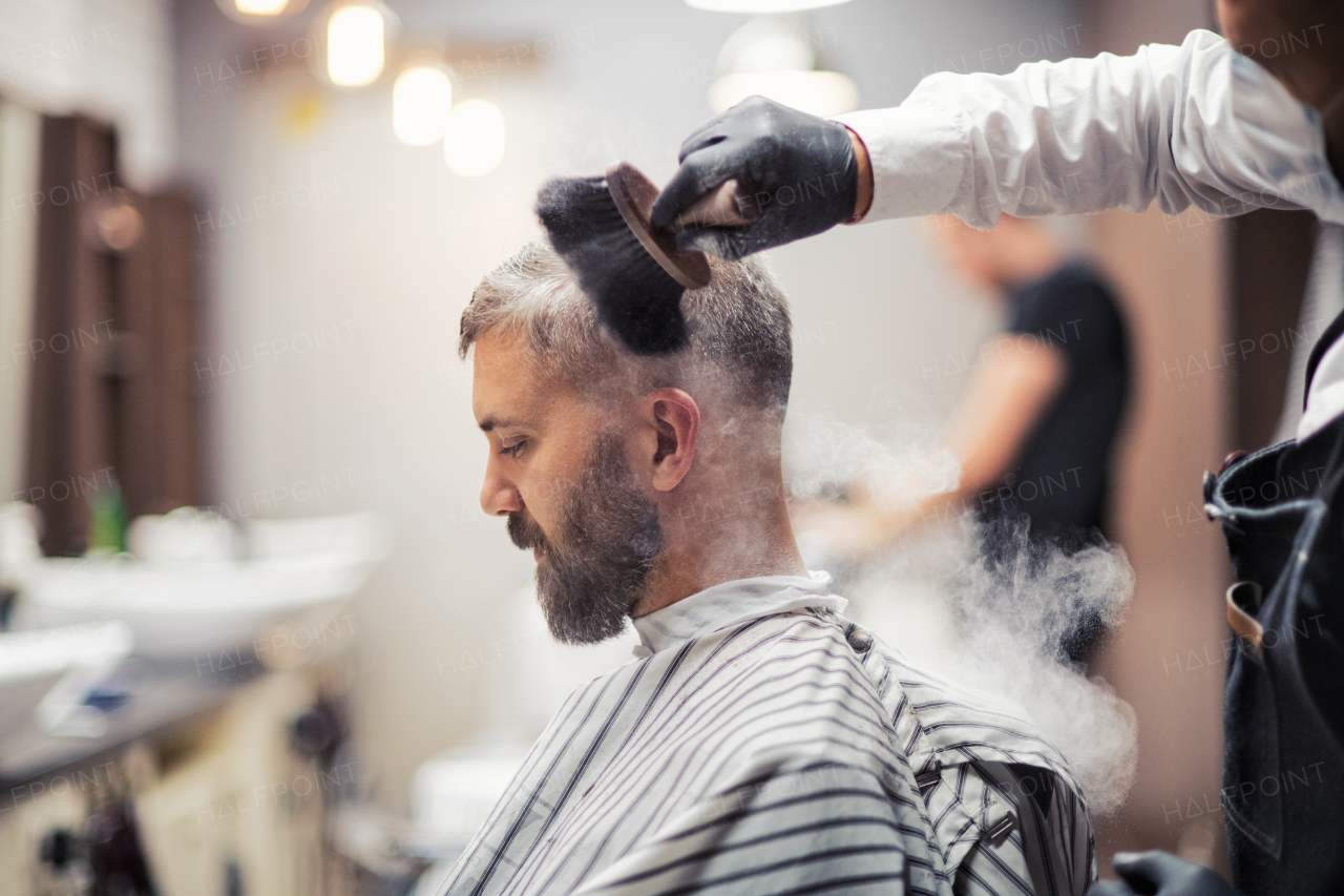 Handsome hipster man client visiting haidresser and hairstylist in barber shop, smoking a pipe.