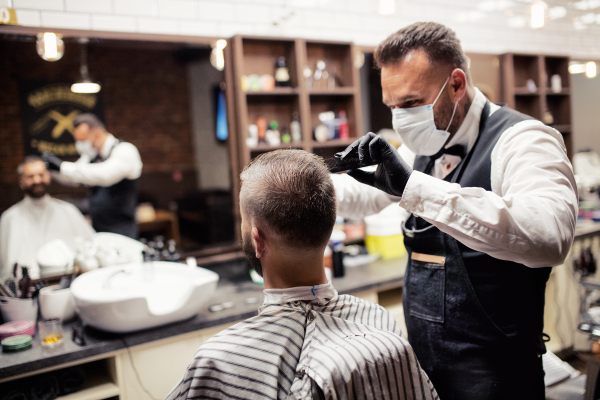 Handsome hipster man client visiting haidresser and hairstylist in barber shop.