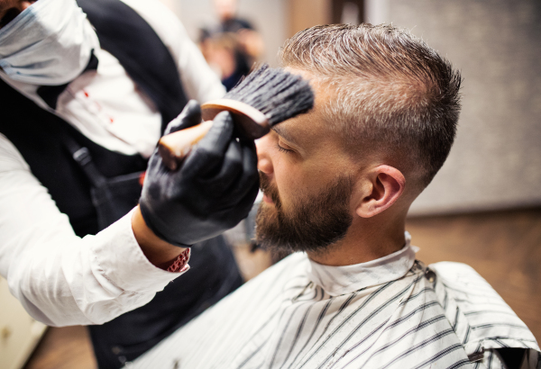 Handsome hipster man client visiting haidresser and hairstylist in barber shop.