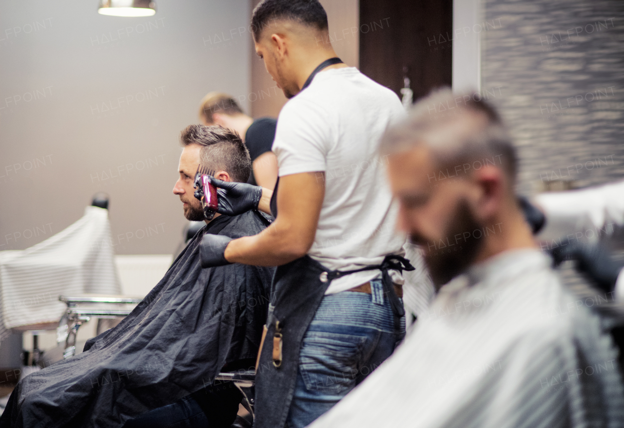 Two man clients visiting haidresser and hairstylist in barber shop.