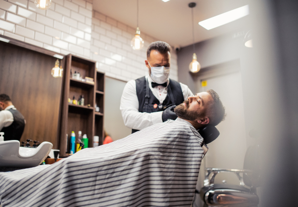 Handsome hipster man client visiting haidresser and hairstylist in barber shop.