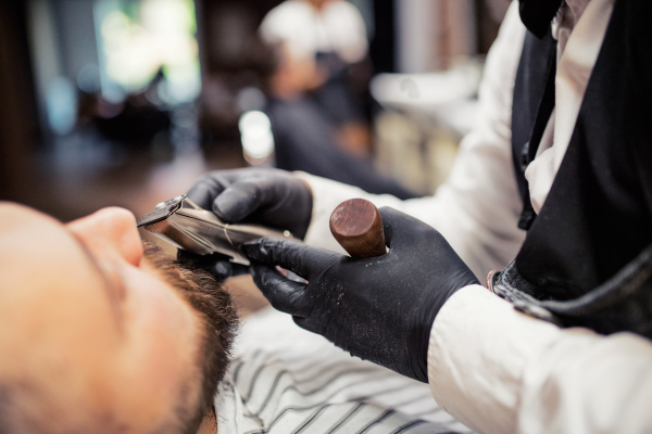 Handsome hipster man client visiting haidresser and hairstylist in barber shop.