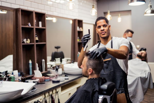 A hipster man client visiting haidresser and hairstylist in barber shop.