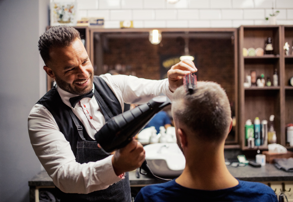 Handsome hipster man client visiting haidresser and hairstylist in barber shop.