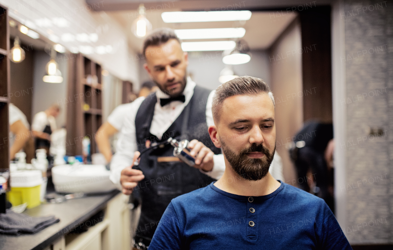 Handsome hipster man client visiting haidresser and hairstylist in barber shop.