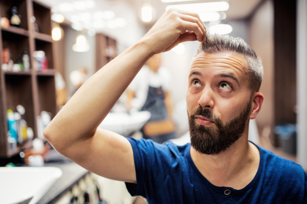 Handsome hipster man client visiting haidresser and hairstylist in barber shop.