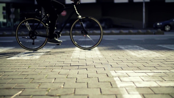 Midsection of unrecognizable male cyclist cycling on an electrobike in city. Slow motion.