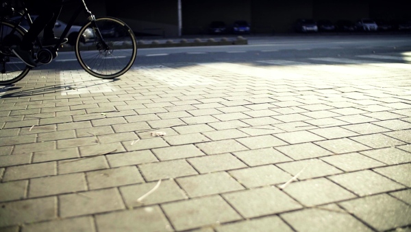 Midsection of unrecognizable male cyclist cycling on an electrobike in city. Slow motion.